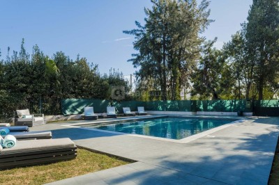 Deux fauteuils en rotin et une table basse avec une tasse, sur une terrasse donnant sur un jardin verdoyant.