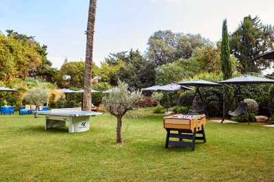 Deux fauteuils en rotin et une table basse avec une tasse, sur une terrasse donnant sur un jardin verdoyant.