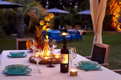 Deux fauteuils en rotin et une table basse avec une tasse, sur une terrasse donnant sur un jardin verdoyant.