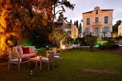 Deux fauteuils en rotin et une table basse avec une tasse, sur une terrasse donnant sur un jardin verdoyant.