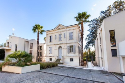 Deux fauteuils en rotin et une table basse avec une tasse, sur une terrasse donnant sur un jardin verdoyant.