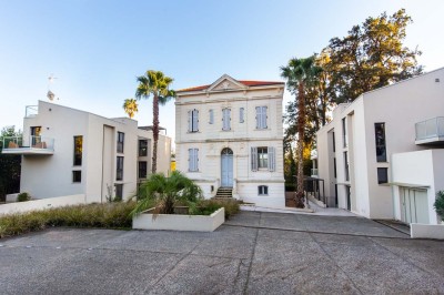 Deux fauteuils en rotin et une table basse avec une tasse, sur une terrasse donnant sur un jardin verdoyant.