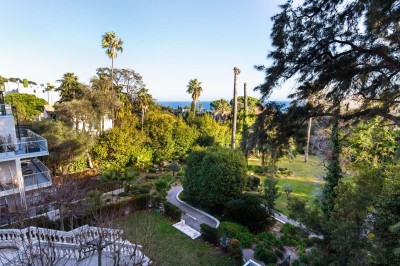Deux fauteuils en rotin et une table basse avec une tasse, sur une terrasse donnant sur un jardin verdoyant.