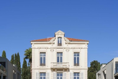 Deux fauteuils en rotin et une table basse avec une tasse, sur une terrasse donnant sur un jardin verdoyant.