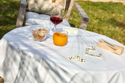 Deux fauteuils en rotin et une table basse avec une tasse, sur une terrasse donnant sur un jardin verdoyant.
