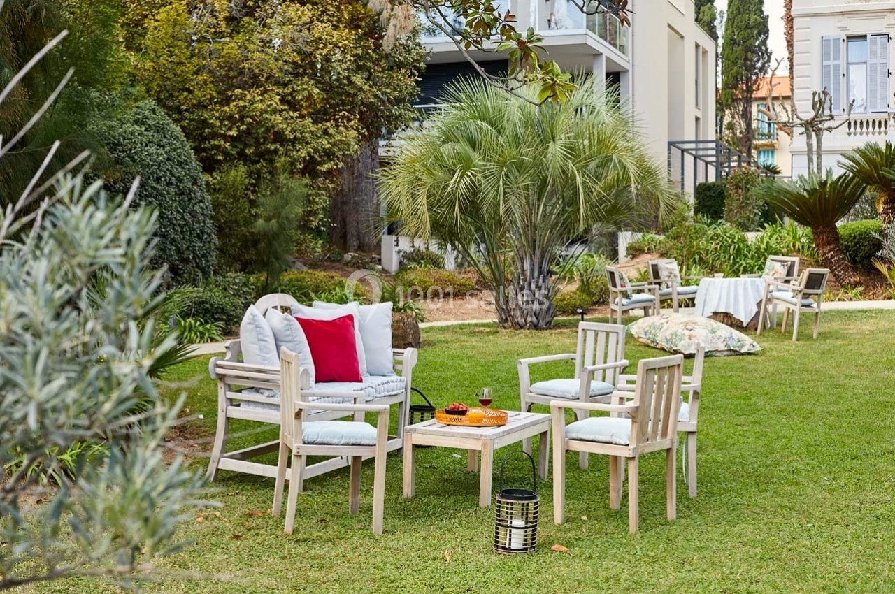 Mobilier de jardin en bois clair disposé sur une pelouse, entouré de végétation et d'arbustes.