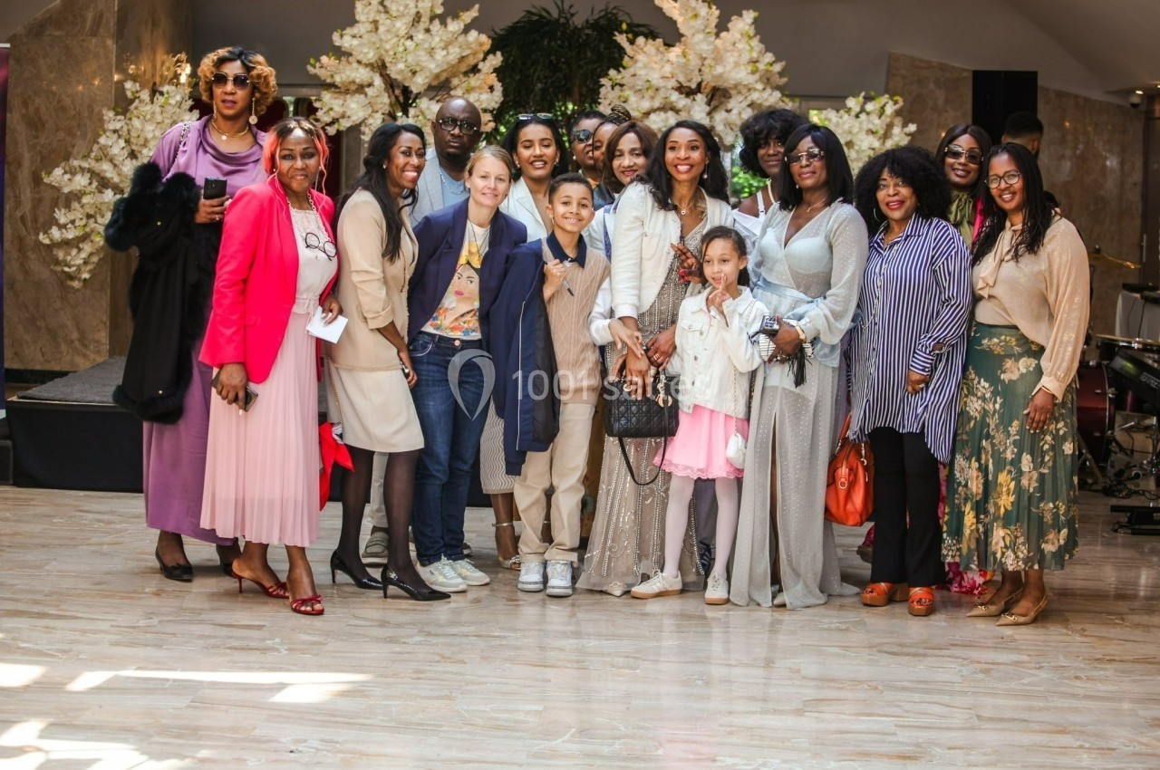 Un groupe de personnes pose ensemble dans un espace intérieur décoré de fleurs blanches.