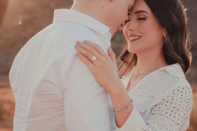 Un chanteur sur scène, vêtu de blanc, levant un bras sous des lumières de spectacle et un écran en arrière-plan.