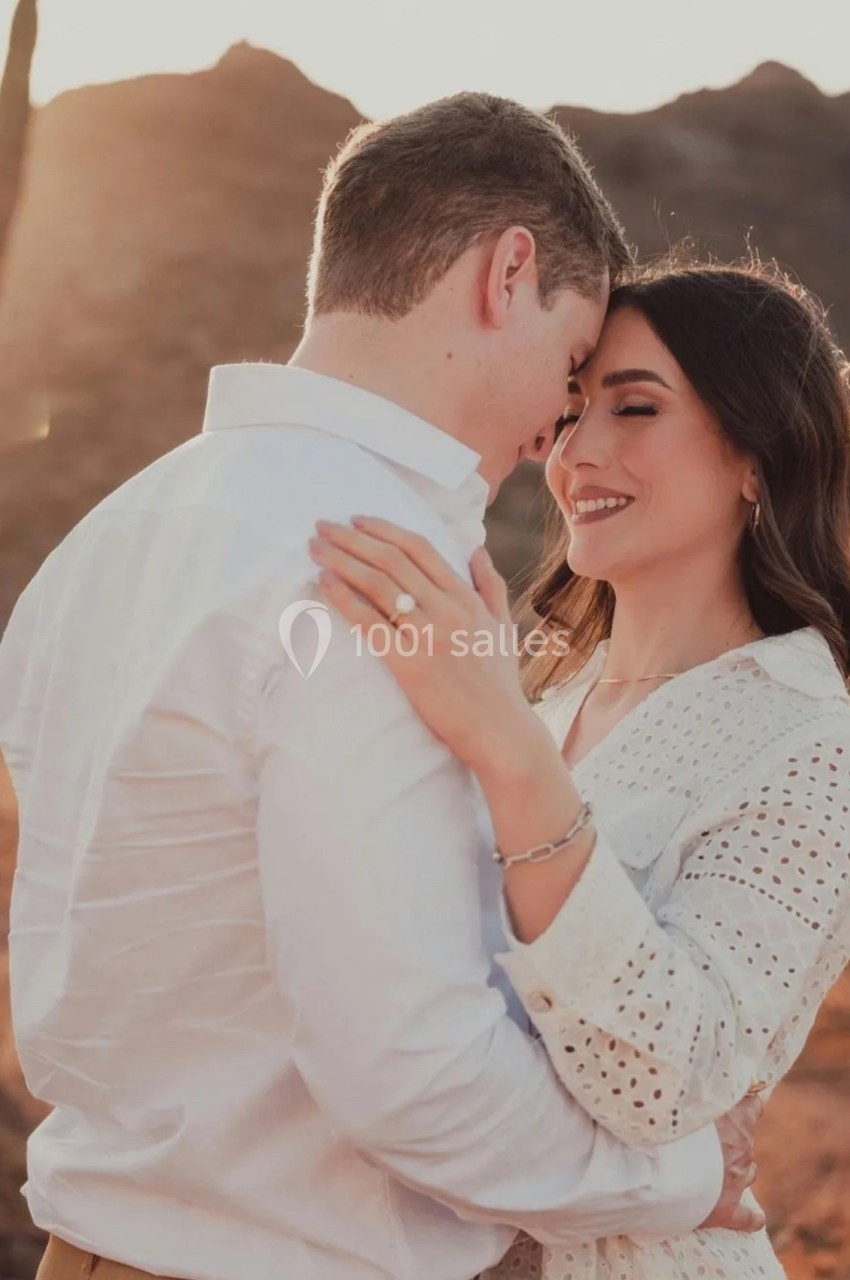 Un couple s'enlace tendrement dans un paysage désertique au coucher du soleil.