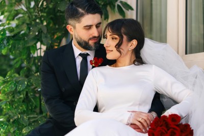 Un chanteur sur scène, vêtu de blanc, levant un bras sous des lumières de spectacle et un écran en arrière-plan.