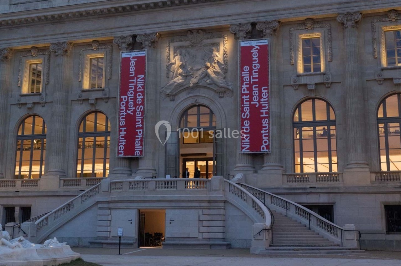 Façade d'un bâtiment historique avec des bannières annonçant une exposition d'artistes contemporains.