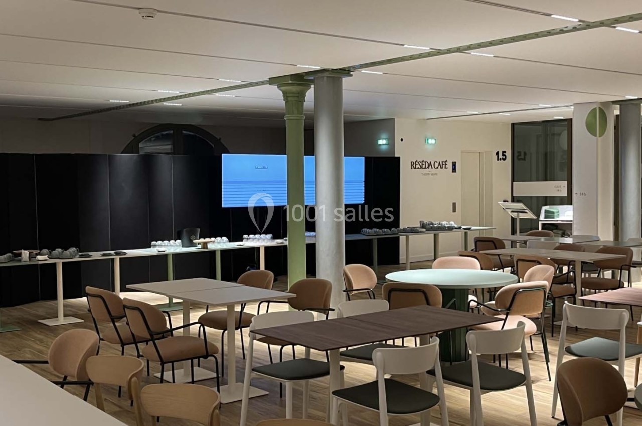 Salle de réunion moderne avec tables, chaises et écrans de présentation, éclairée par des lumières artificielles.