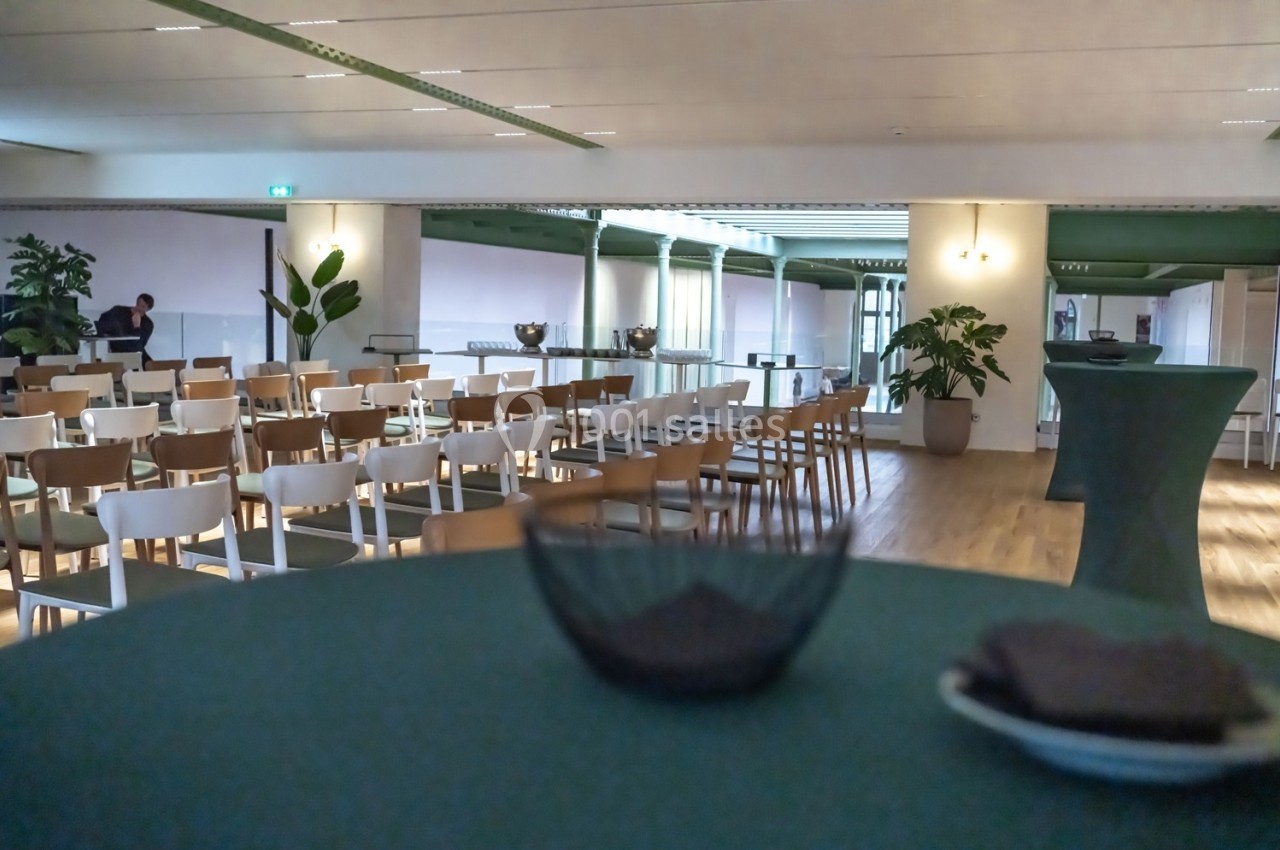 Salle de conférence lumineuse avec des rangées de chaises, des plantes et une table en premier plan.