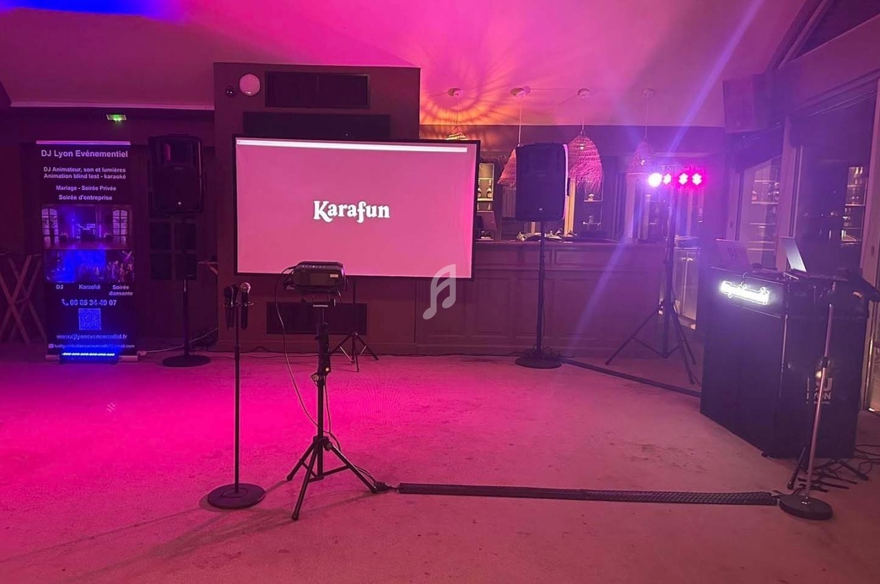 Salle équipée pour un karaoké avec écran projetant ’Karafun’, micros sur pied et éclairage coloré.