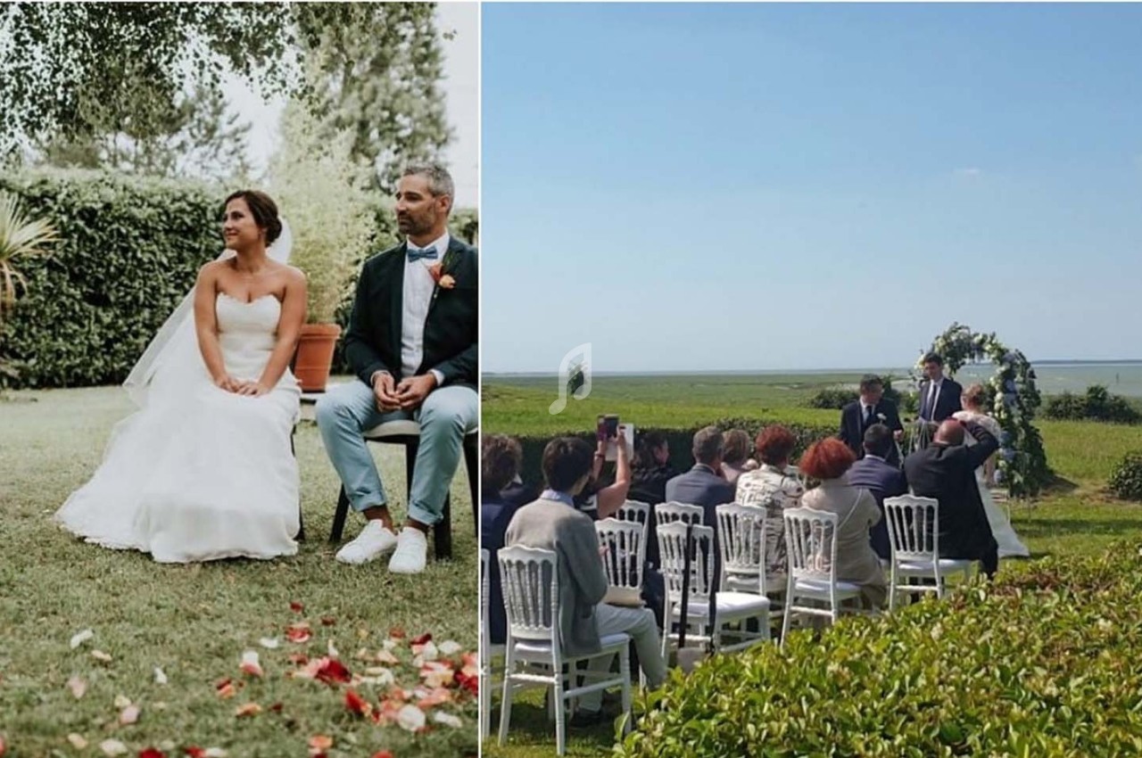 Un couple assis lors d'une cérémonie de mariage en extérieur, entouré d'invités et de verdure.