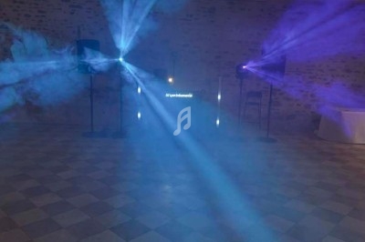 Groupe de personnes dansant sous des lumières bleues dans une ambiance festive en intérieur.