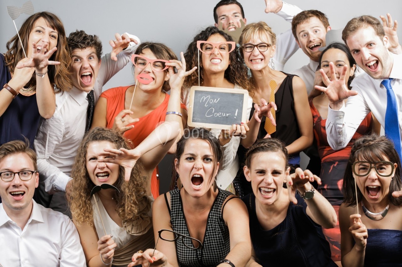 Un groupe de personnes souriantes et expressives posant de manière amusante avec des accessoires et une ardoise.