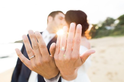 Une femme en robe blanche et talons pose son pied sur un ballon de football sur une pelouse.