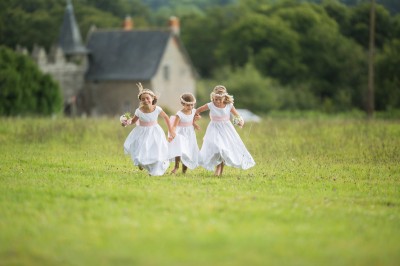 Une femme en robe blanche et talons pose son pied sur un ballon de football sur une pelouse.