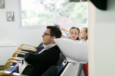 Une femme en robe blanche et talons pose son pied sur un ballon de football sur une pelouse.
