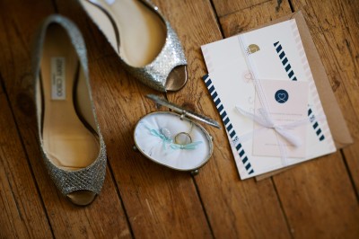 Une femme en robe blanche et talons pose son pied sur un ballon de football sur une pelouse.