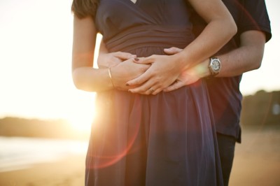 Une femme en robe blanche et talons pose son pied sur un ballon de football sur une pelouse.
