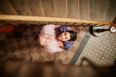 Une femme en robe blanche et talons pose son pied sur un ballon de football sur une pelouse.
