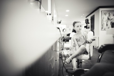 Une femme en robe blanche et talons pose son pied sur un ballon de football sur une pelouse.