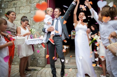 Une femme en robe blanche et talons pose son pied sur un ballon de football sur une pelouse.