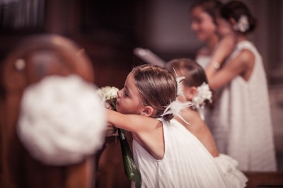 Une femme en robe blanche et talons pose son pied sur un ballon de football sur une pelouse.