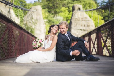 Une femme en robe blanche et talons pose son pied sur un ballon de football sur une pelouse.