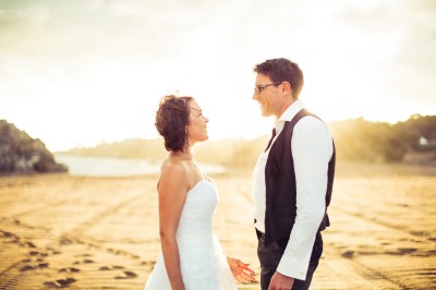 Une femme en robe blanche et talons pose son pied sur un ballon de football sur une pelouse.