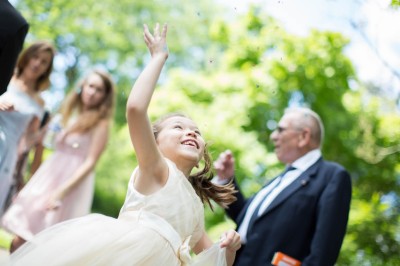 Une femme en robe blanche et talons pose son pied sur un ballon de football sur une pelouse.