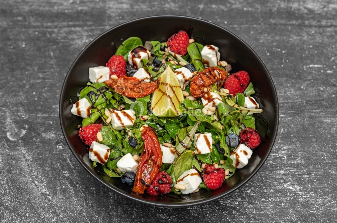 Salade composée avec épinards, framboises, myrtilles, tomates séchées, feta, graines et filet de vinaigre balsamique.