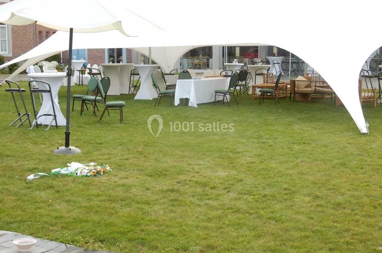 Tente blanche installée sur une pelouse avec tables, chaises et décorations pour un événement en extérieur.