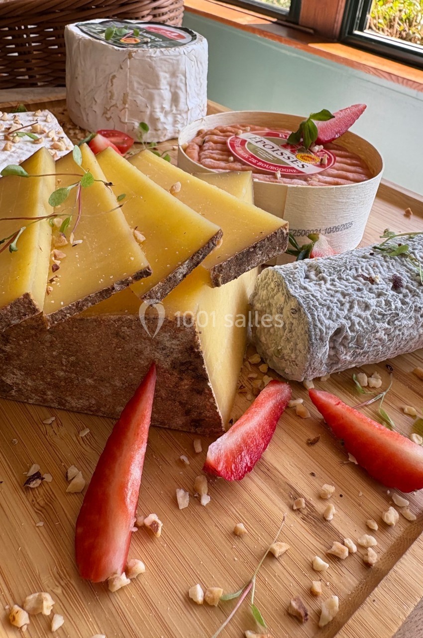 Plateau en bois avec fromages variés, tranches de fromage à pâte dure, fraises fraîches et noix concassées.