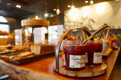 Miniature Location salle Arras (Pas-de-Calais) - Mercure Arras Centre Gare #10 Pots de confiture de fraise avec cuillères sur une table en bois, entourés de pains et viennoiseries dans un buffet.