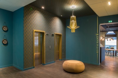 Miniature Location salle Arras (Pas-de-Calais) - Mercure Arras Centre Gare #14 Feuilles vertes dans un vase doré sur une étagère près d'une fenêtre donnant sur une rue urbaine avec bâtiments et grue.