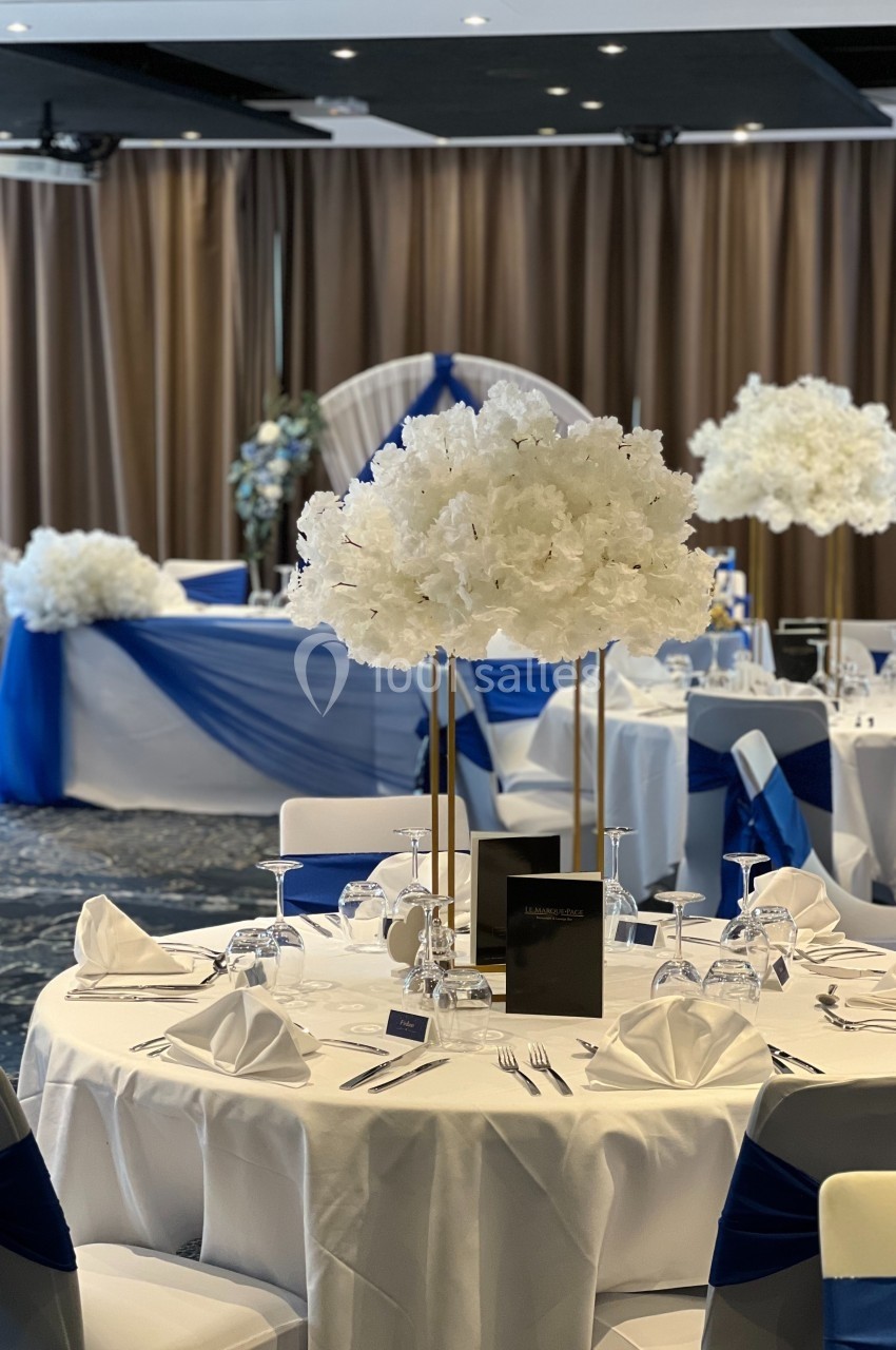 Location salle Marcq-en-Baroeul (Nord) - Mercure Lille Marcq en Baroeul #7 Salle de réception décorée pour un événement, avec tables dressées, nappes blanches et accents bleus, et centres de table…