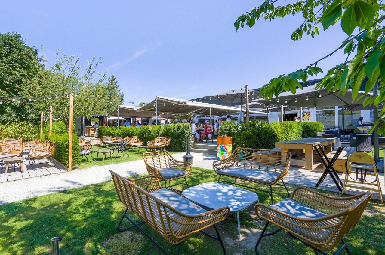 Location salle Marcq-en-Baroeul (Nord) - Mercure Lille Marcq en Baroeul #9 Terrasse extérieure avec mobilier en rotin, tables basses, parasols et verdure sous un ciel dégagé.