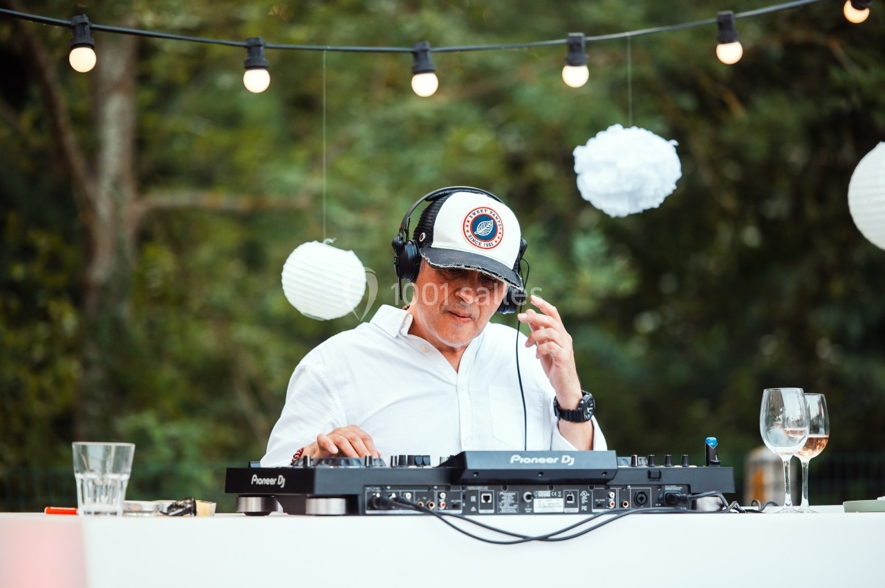 Location salle Marcq-en-Baroeul (Nord) - Mercure Lille Marcq en Baroeul #14 Un DJ mixe en plein air sous des guirlandes lumineuses, entouré de décorations blanches suspendues.