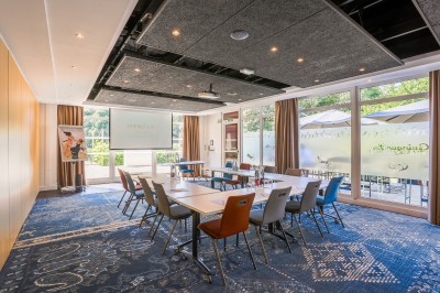 Miniature Location salle Marcq-en-Baroeul (Nord) - Mercure Lille Marcq en Baroeul #22 Salle de conférence avec des rangées de chaises colorées face à un écran de projection allumé.