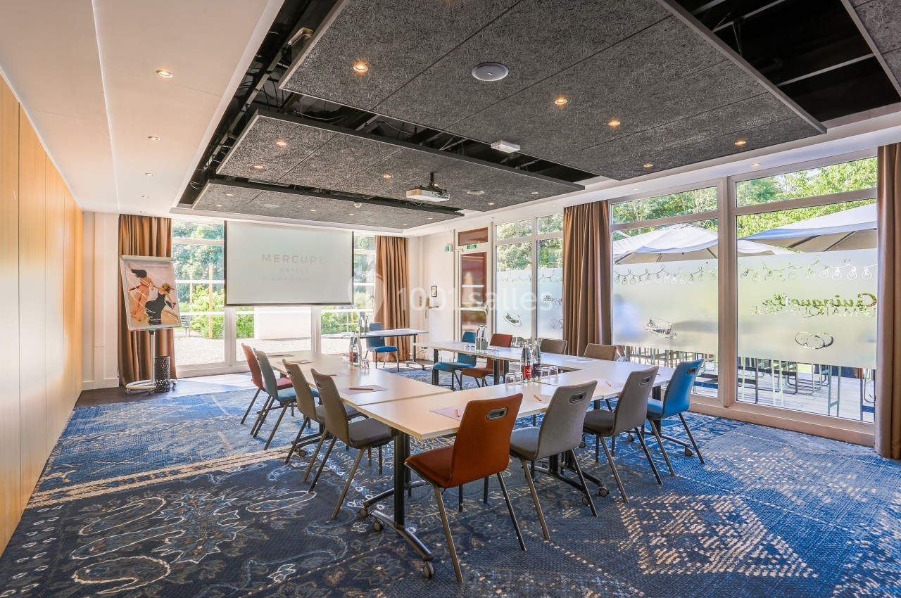Location salle Marcq-en-Baroeul (Nord) - Mercure Lille Marcq en Baroeul #22 Salle de réunion lumineuse avec tables disposées en U, chaises colorées et grandes baies vitrées donnant sur une terrasse.