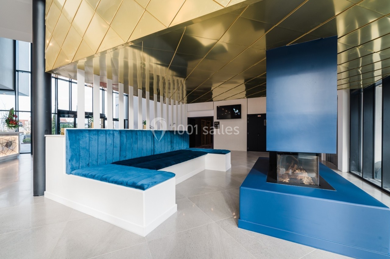 Banquette bleue en velours et cheminée moderne dans un espace intérieur lumineux avec plafond doré.