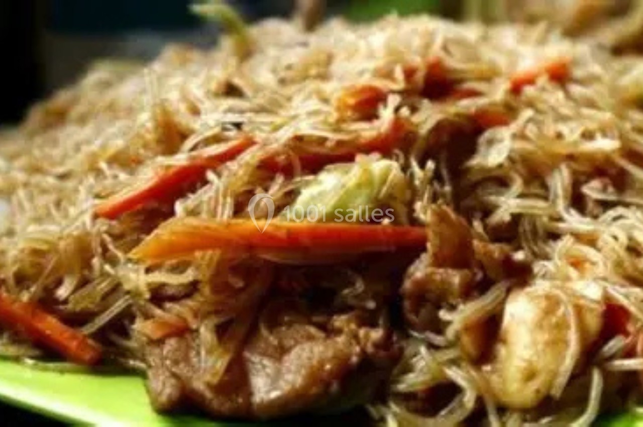 Assiette de nouilles de riz sautées avec légumes et morceaux de viande.