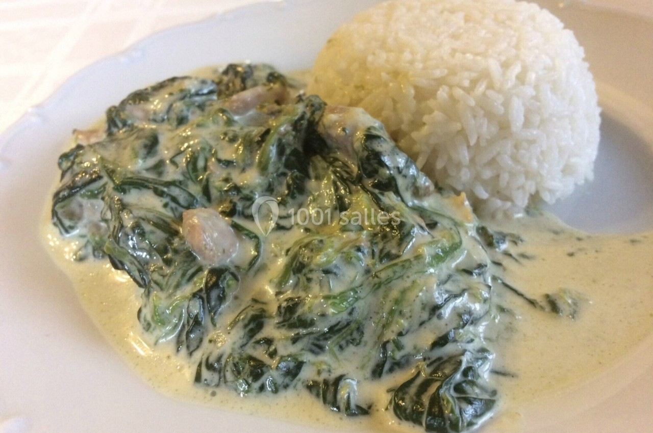 Plat composé d'épinards à la crème accompagnés d'une portion de riz blanc sur une assiette blanche.