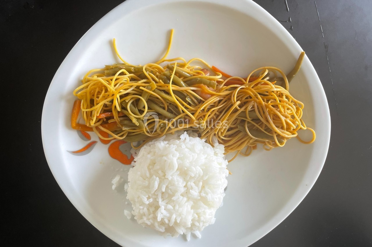 Assiette contenant du riz blanc et des nouilles sautées aux légumes sur une table noire.