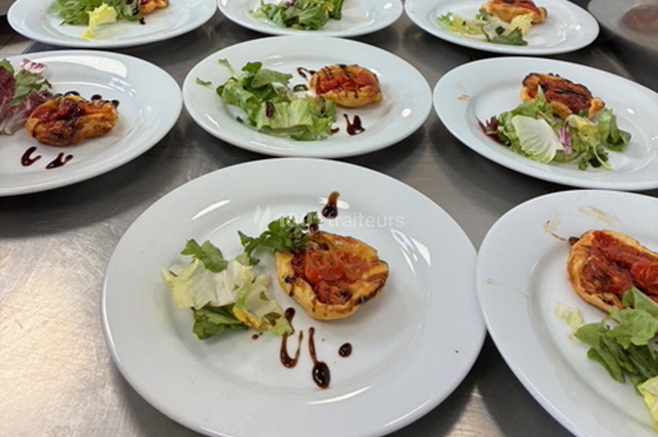 Assiettes contenant des tartelettes salées garnies de légumes et accompagnées de salade verte avec un filet de sauce.