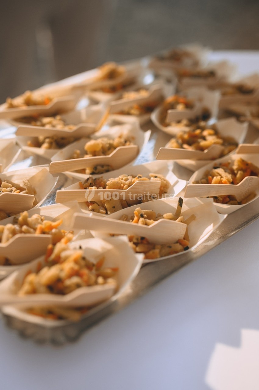 Plateau de petites portions de salade de légumes servies dans des coupelles en bois sur une table blanche.