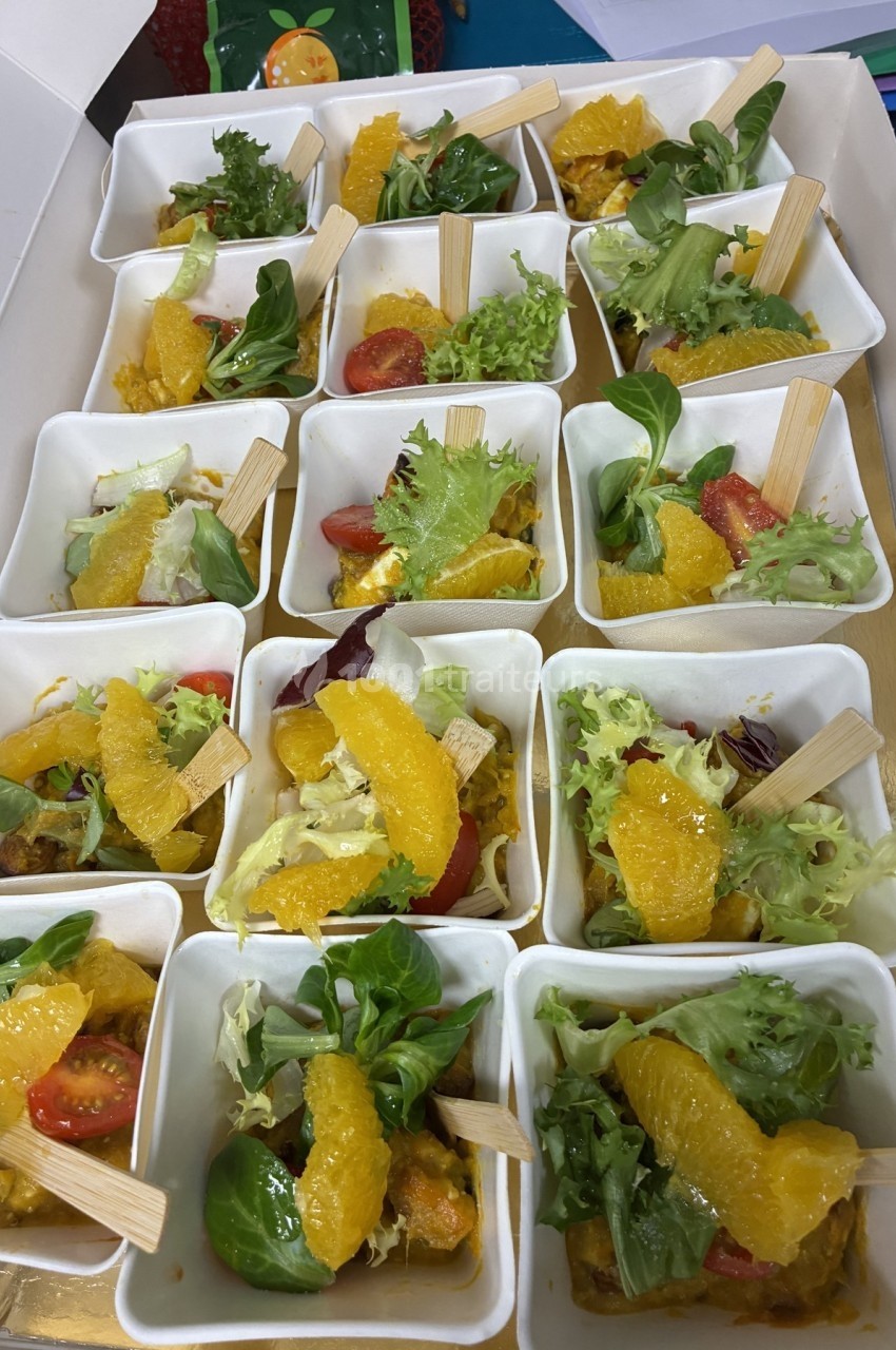 Assortiment de verrines contenant des salades colorées avec segments d'orange, tomates cerises et feuilles de salade.